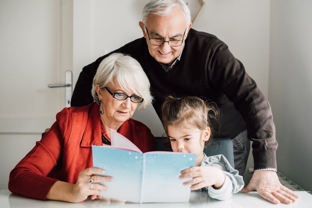 Grandparents reading a book with granddaughter